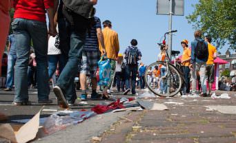 A group of people walk down a street leaving a trail of litter behind them