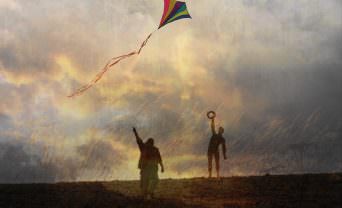 two people flying a kite at sunset