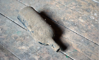 glass bottle covered in dust on floorboards