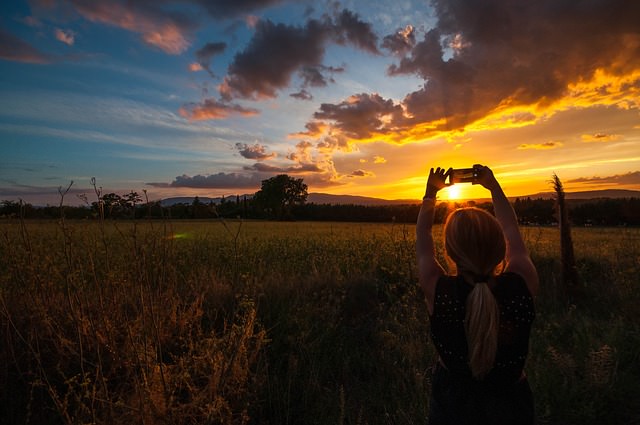 Woman takes photo of the sunset with her smartphone