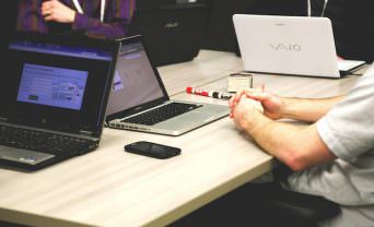 A project team with laptops sit around a table